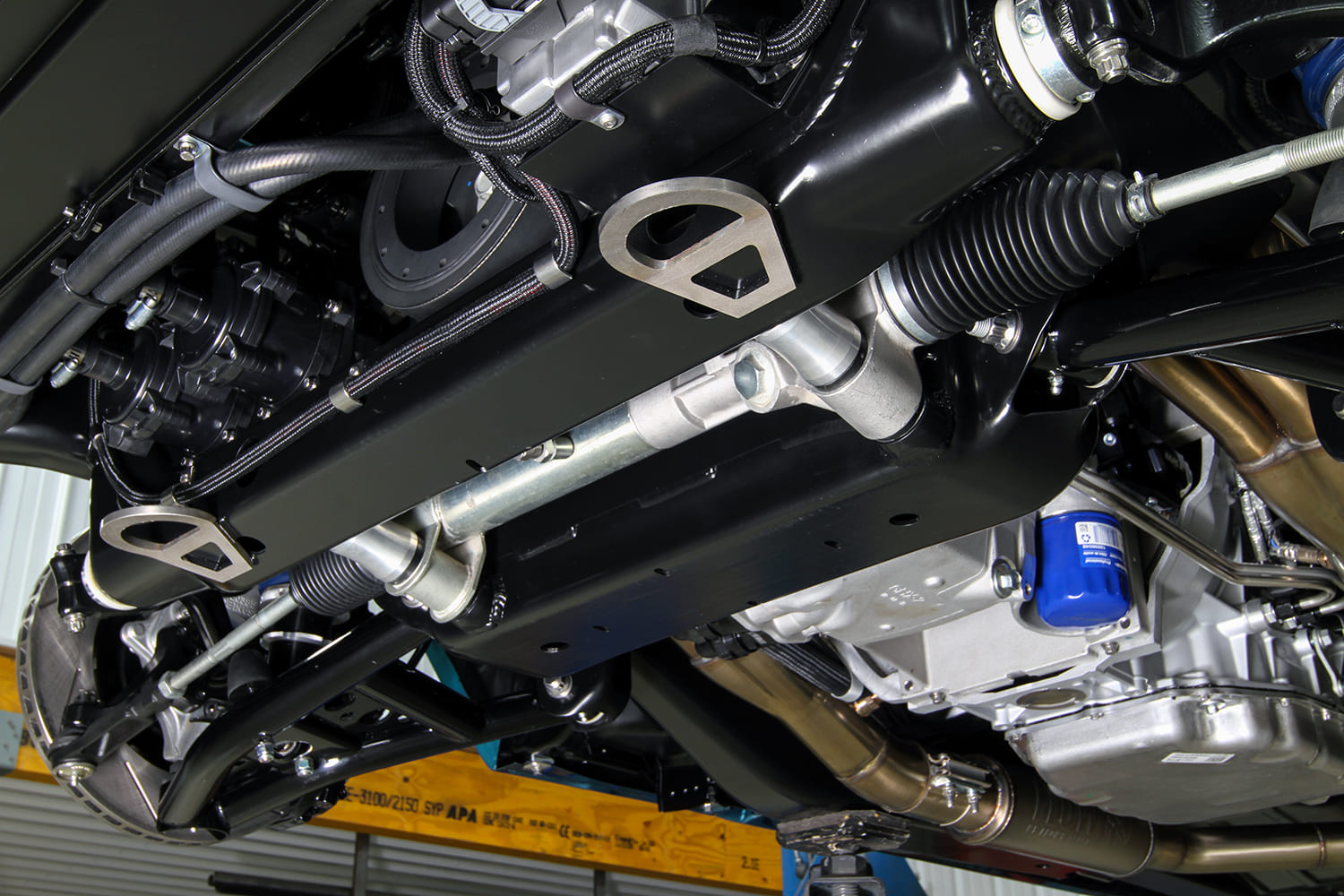 Underside view of the front chassis displaying the rack-and-pinion steering assembly, front sway bar, and engine oil pan.