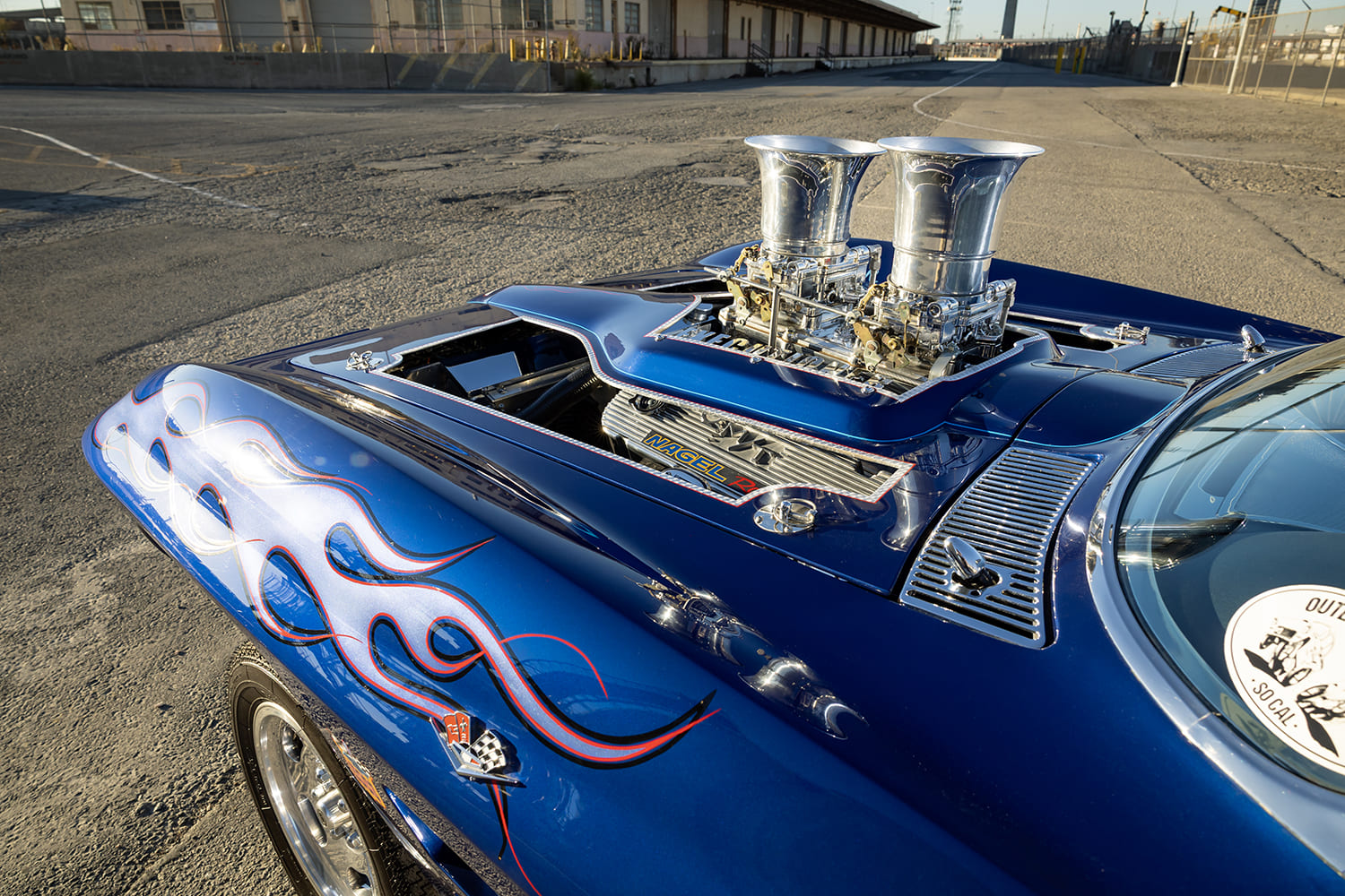 Front quarter angle across the hood displaying purple-edged flame graphics, hood pins, and protruding polished air horns.