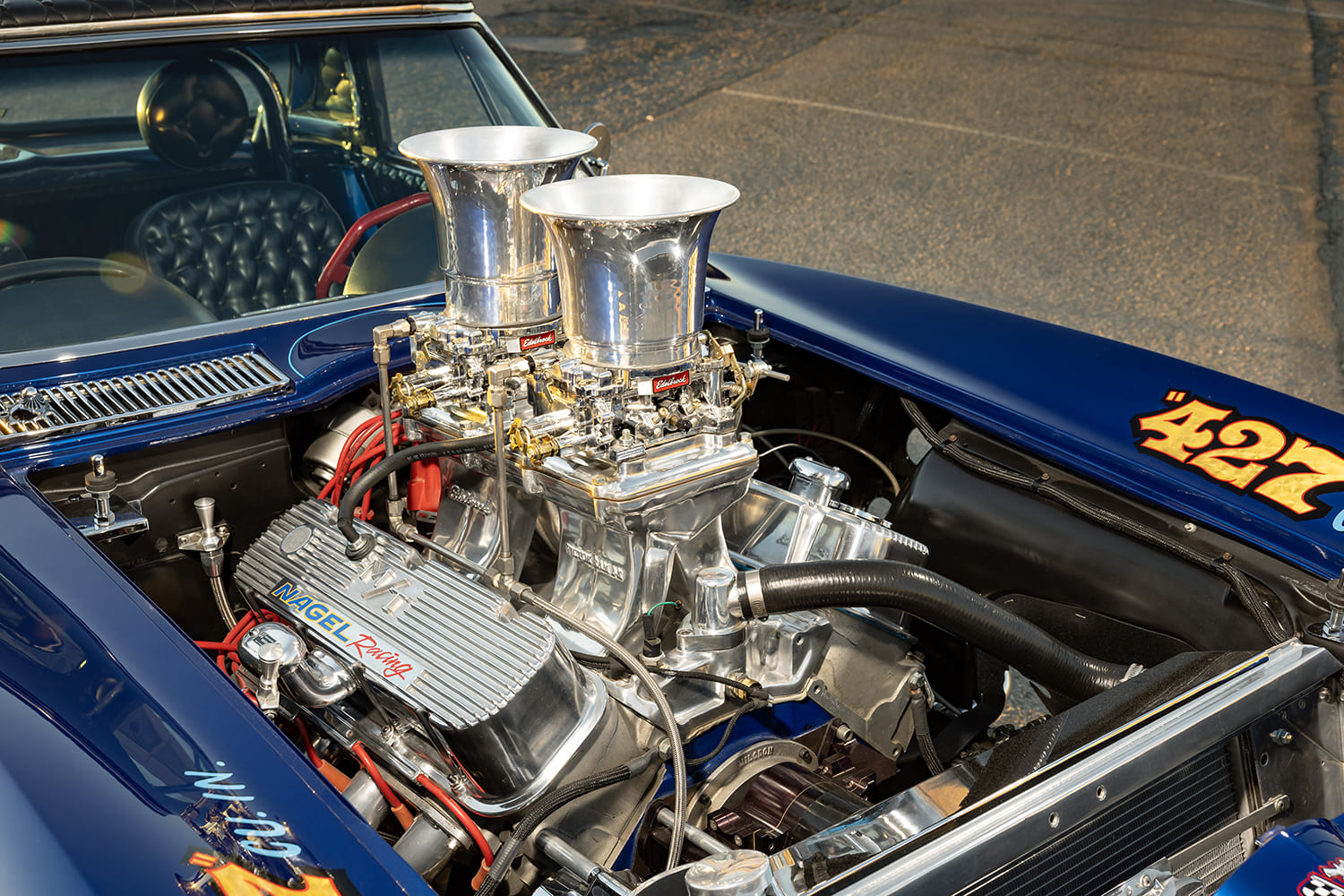 Three-quarter engine bay view of the dual four-barrel carburetors, tall stacks, finned Nagel Racing valve covers, and aluminum radiator.