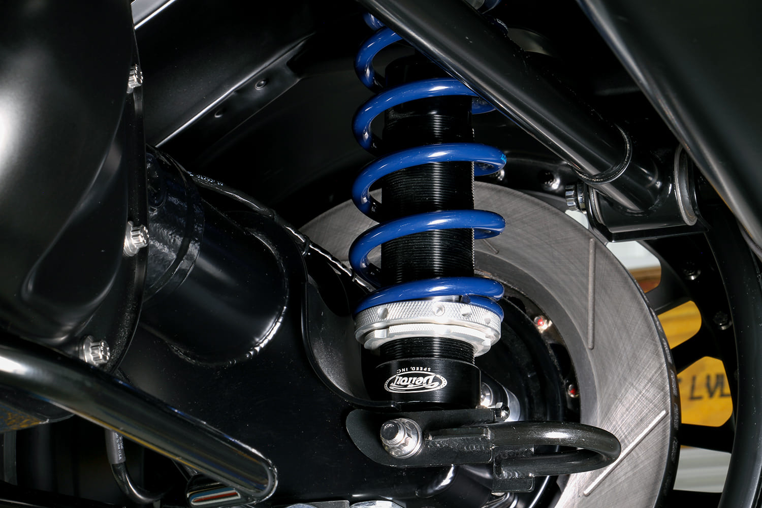 Macro shot of a Detroit Speed threaded body rear coilover shock with blue spring and billet adjusting collar.