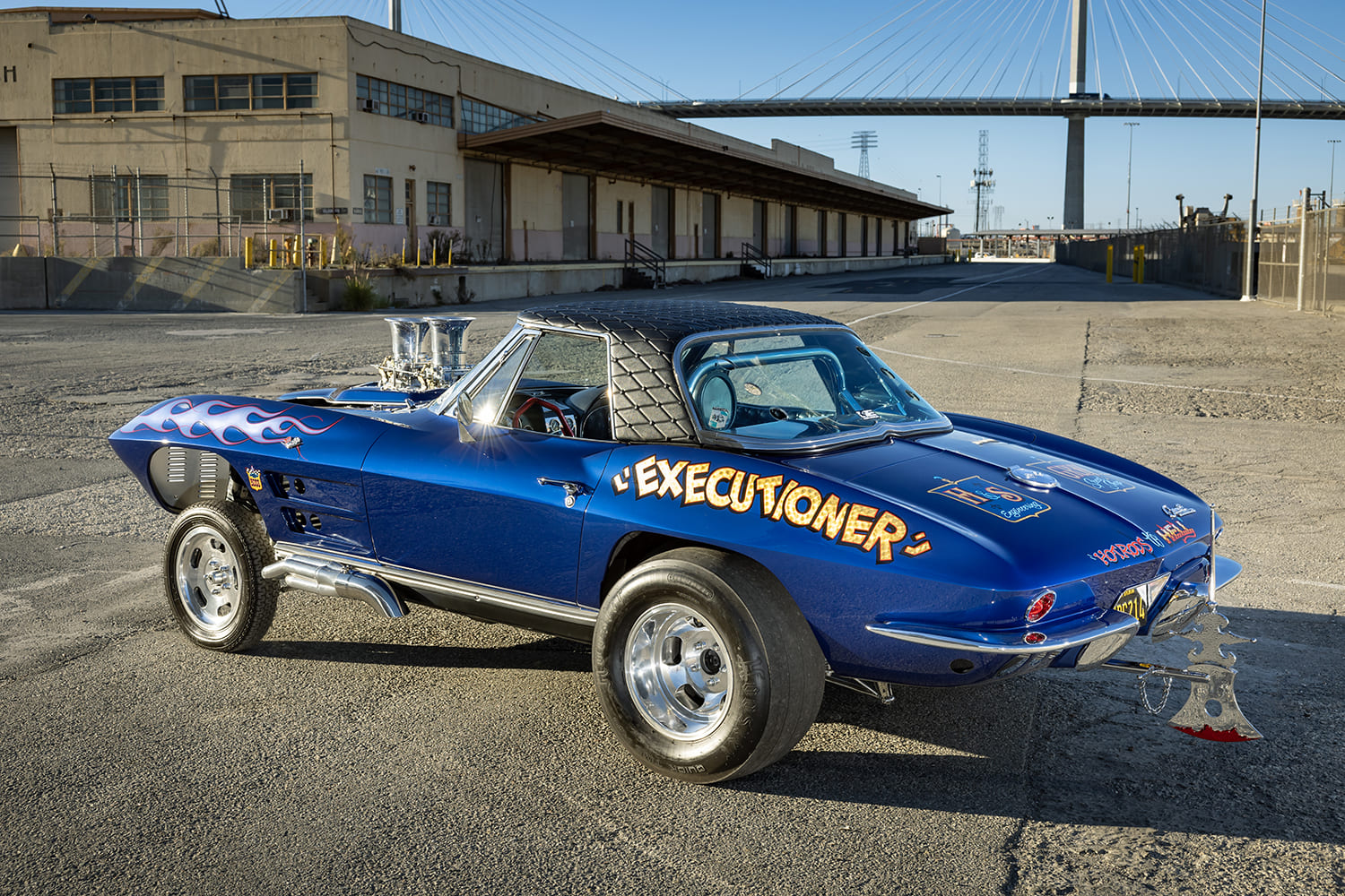 Rear three-quarter view of the blue 1964 Corvette gasser showing the custom executioner axe bumper attachment, wide slicks, and diamond hardtop.