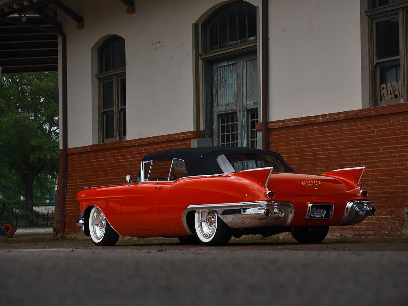 Low rear three-quarter angle showcasing the sculptured rear fender lines, pointed inboard fins, and wraparound stainless steel beauty panels.