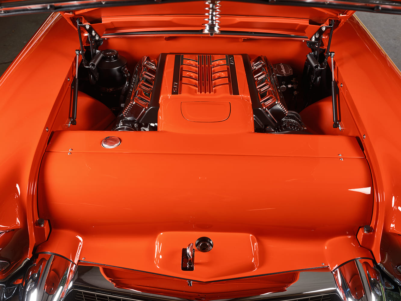 Top-down engine bay overview showing the color-matched smooth closeout panels, recessed radiator cap, and supercharged 6.2L LT5 V8 crate engine.