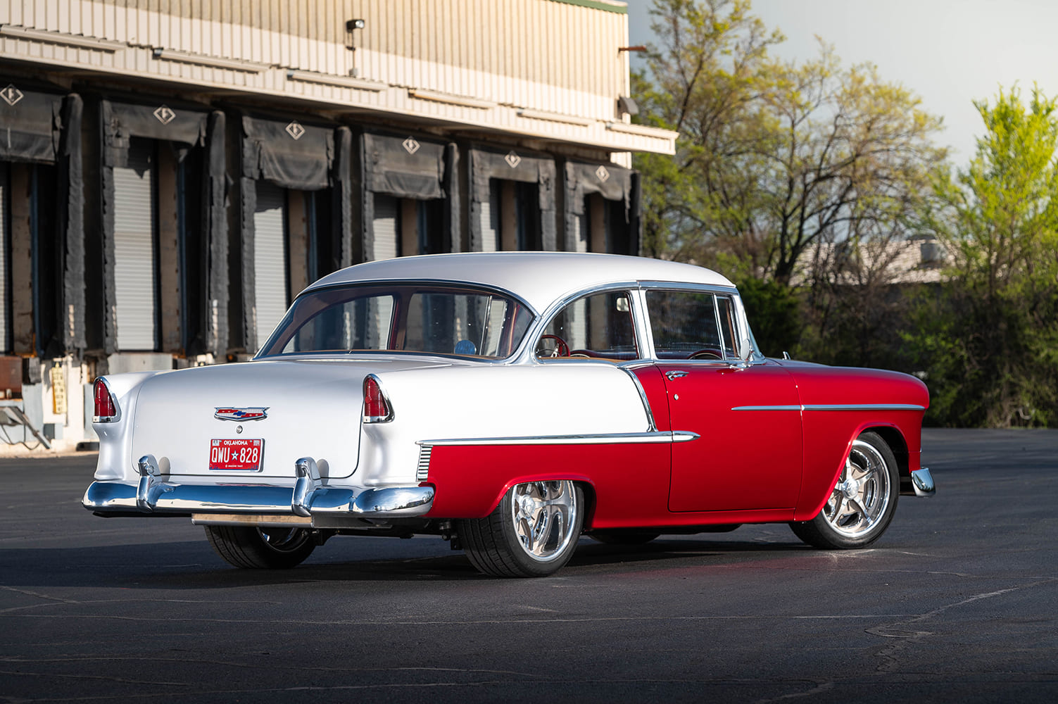 Low-angle rear three-quarter view of the 1955 Chevrolet Bel Air showing the white upper quarter panels, tailfins, bumper, and Oklahoma license plate.