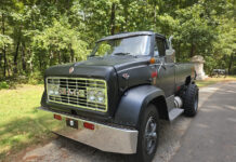 Front three-quarter view of a custom matte black 1967 GMC 7500 pickup truck with chrome front bumper and quad headlights.