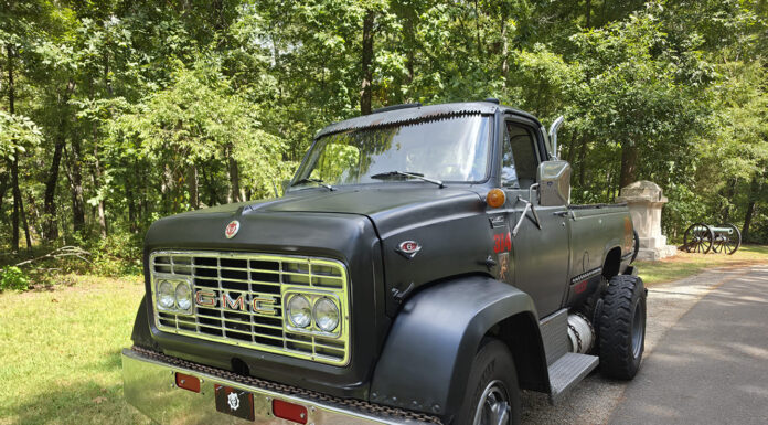 Front three-quarter view of a custom matte black 1967 GMC 7500 pickup truck with chrome front bumper and quad headlights.