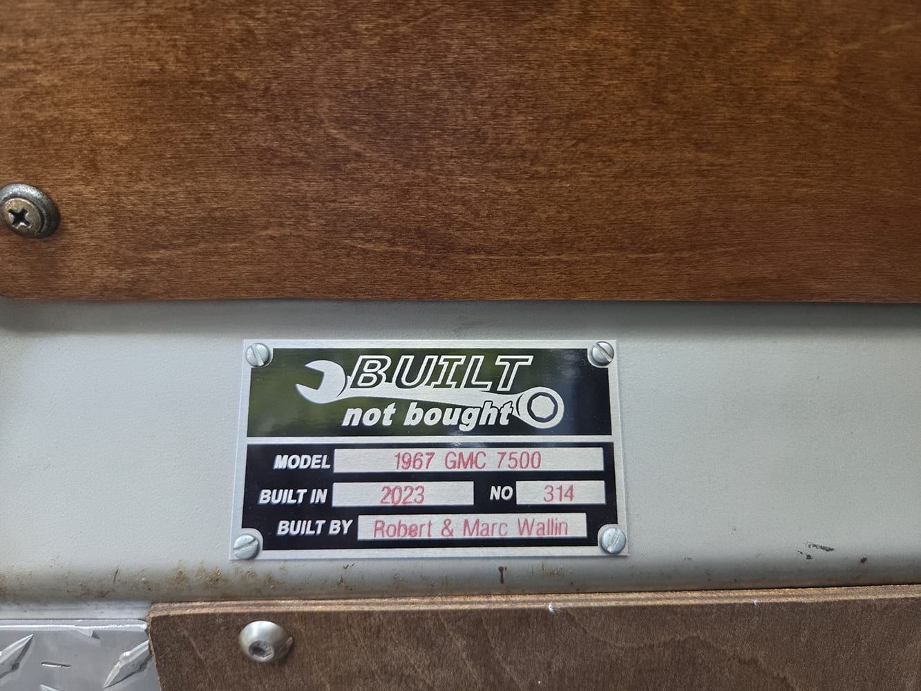 Custom "Built Not Bought" metal identification plate mounted on a 1967 GMC 7500 dash crediting builders Robert and Marc Wallin.