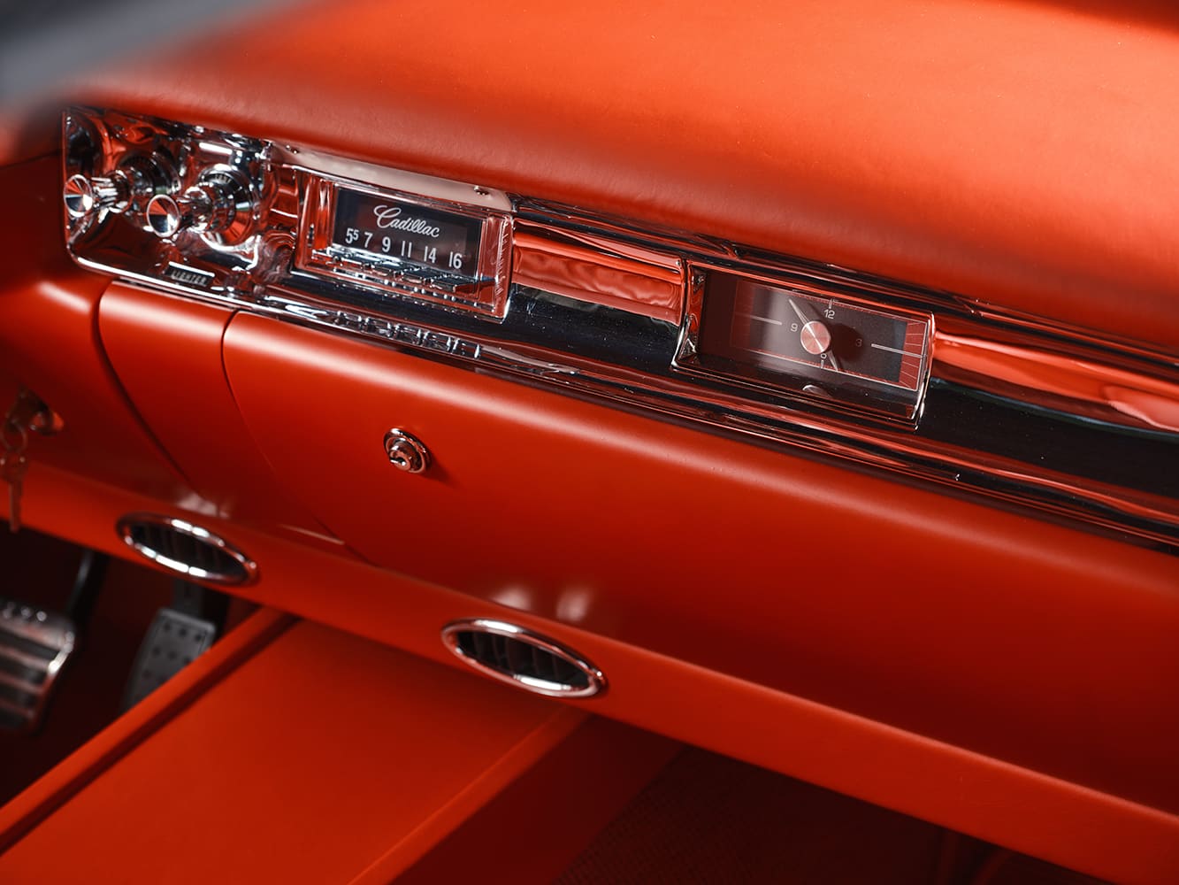 Detail shot of the passenger-side dashboard highlighting the restored chrome-accented Cadillac radio dial, analog clock, and sub-dash A/C registers.