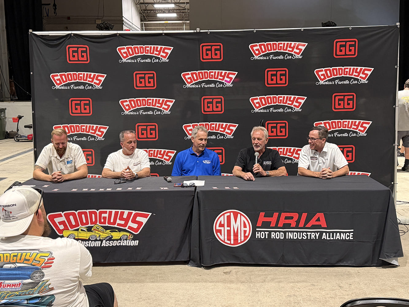 Panel of custom builders and industry experts seated behind a SEMA Hot Rod Industry Alliance (HRIA) and Goodguys branded table during a forum.