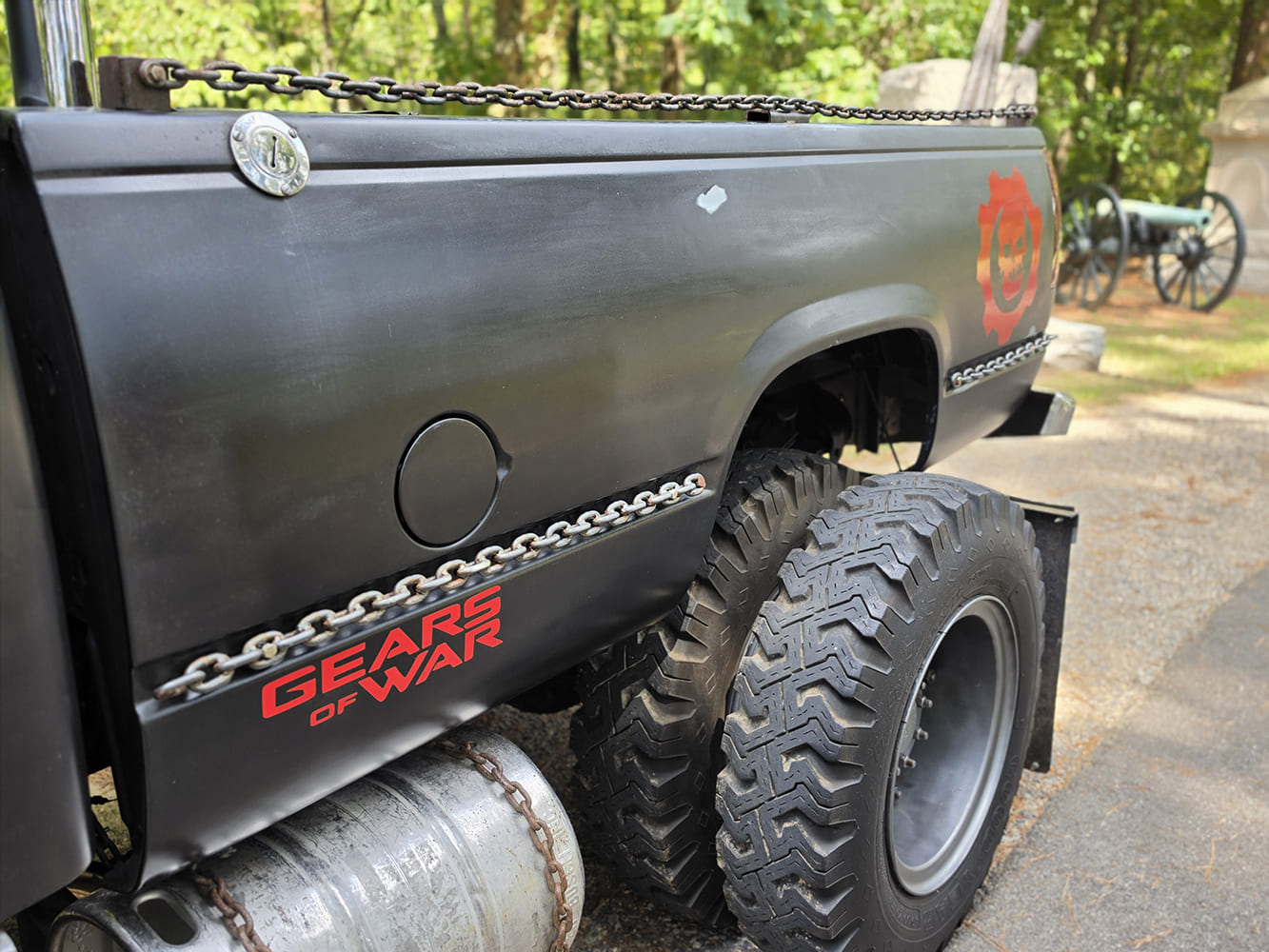 Detail of custom welded chain trim, auxiliary tank, and red Gears of War graphics along the bedside of a 1967 GMC 7500.