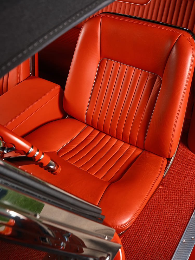 Overhead portrait view looking directly down onto the driver-side custom contoured leather seat with vertical pleats and contrasting welt stitching.