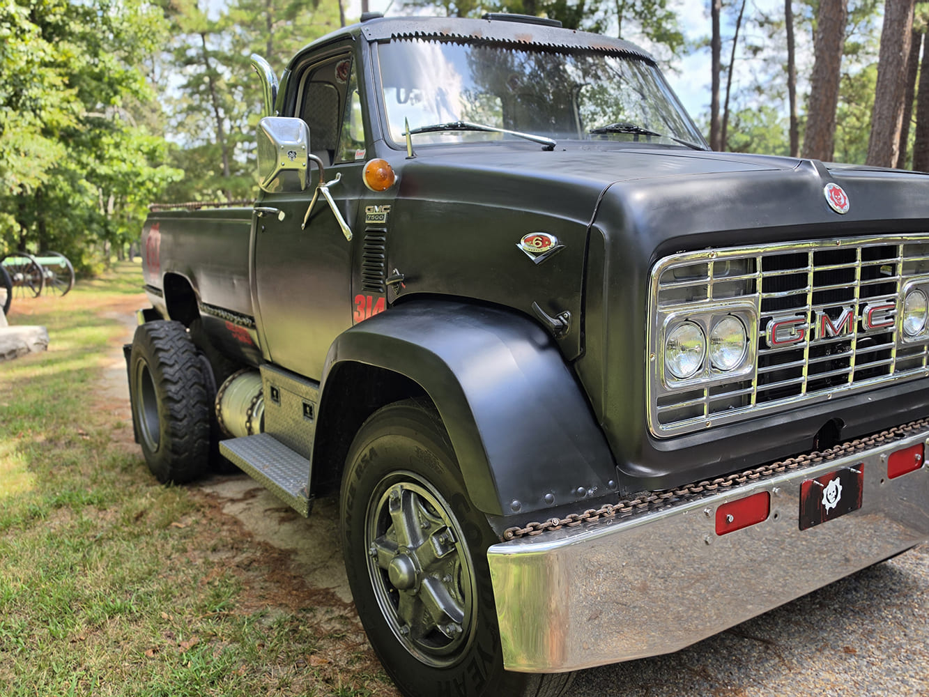 Low-angle front three-quarter view showing the chrome grille, massive front fender flares, and passenger profile of a 1967 GMC 7500.