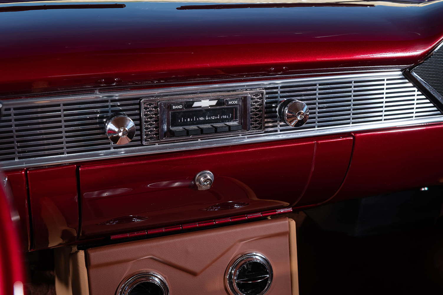 Close-up of the vintage-style digital stereo receiver with Chevrolet bowtie script centered within the ribbed chrome speaker mesh of the dash.