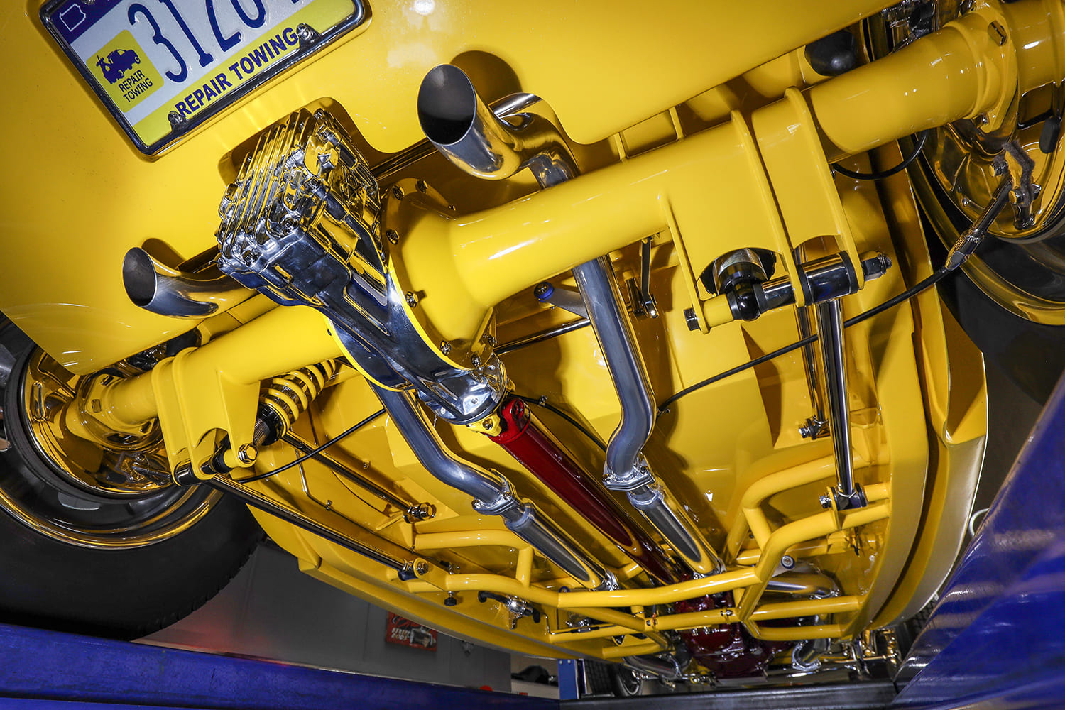 Underside view of the yellow hot rod chassis highlighting the polished finned quick-change rear axle and custom stainless exhaust system.