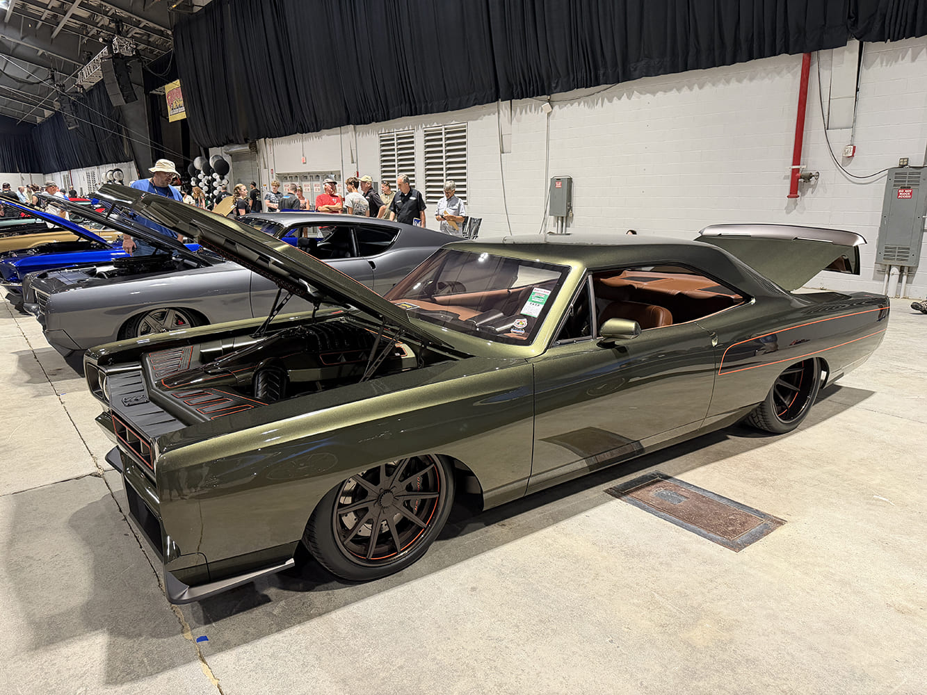 Front three-quarter perspective of an aggressive olive metallic 1968 Plymouth Road Runner restomod with raised hood exposing a supercharged Hemi engine.
