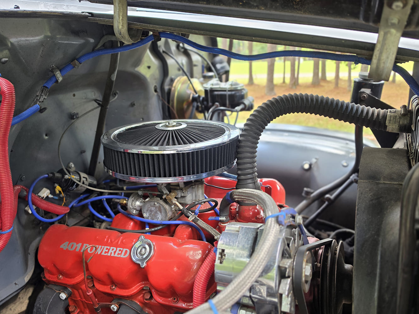 Engine bay detail of a 1967 GMC 7500 highlighting a red GMC 401 cubic-inch big-block V6 engine with round air cleaner.