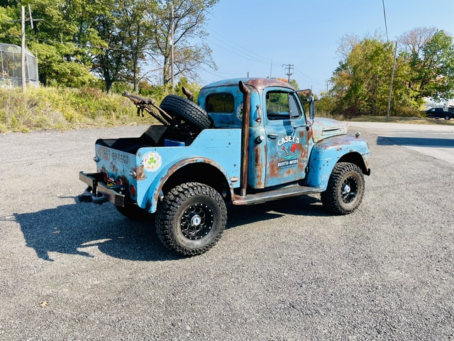 Rear three-quarter perspective showing the custom vintage tow boom assembly, spare tire mount, and tall vertical exhaust stack on the 1949 Ford F2.