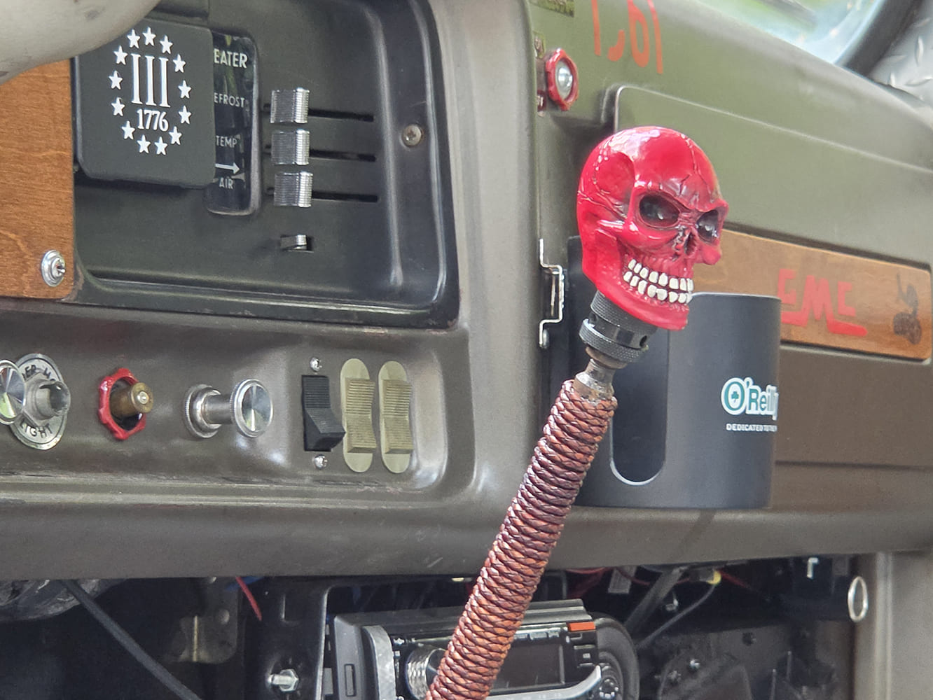 Close-up of a custom carved red skull shift knob and wrapped shifter stick inside a modified 1967 GMC 7500 truck cab.