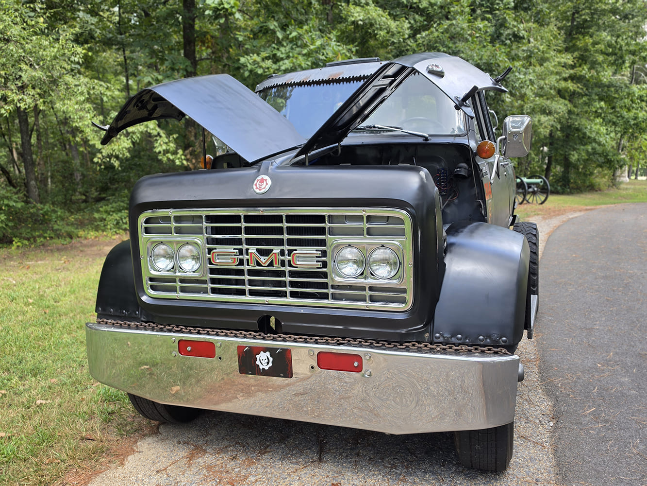 Front view of a custom matte black 1967 GMC 7500 with both sides of its dual butterfly-opening hood raised.