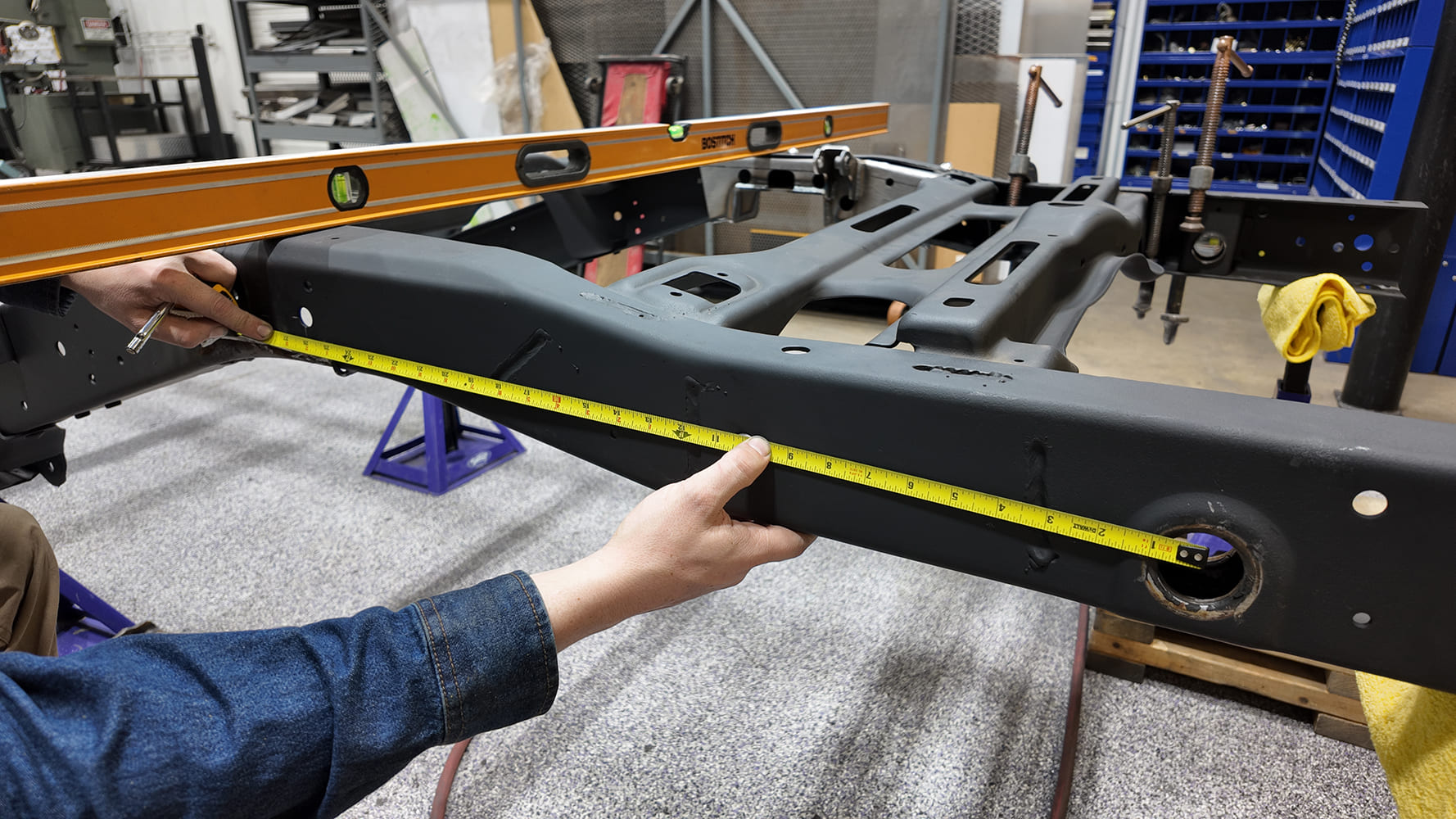 Measuring the Chevy S-10 frame rail with a tape measure to position the Detroit Speed rear suspension frame notch template.