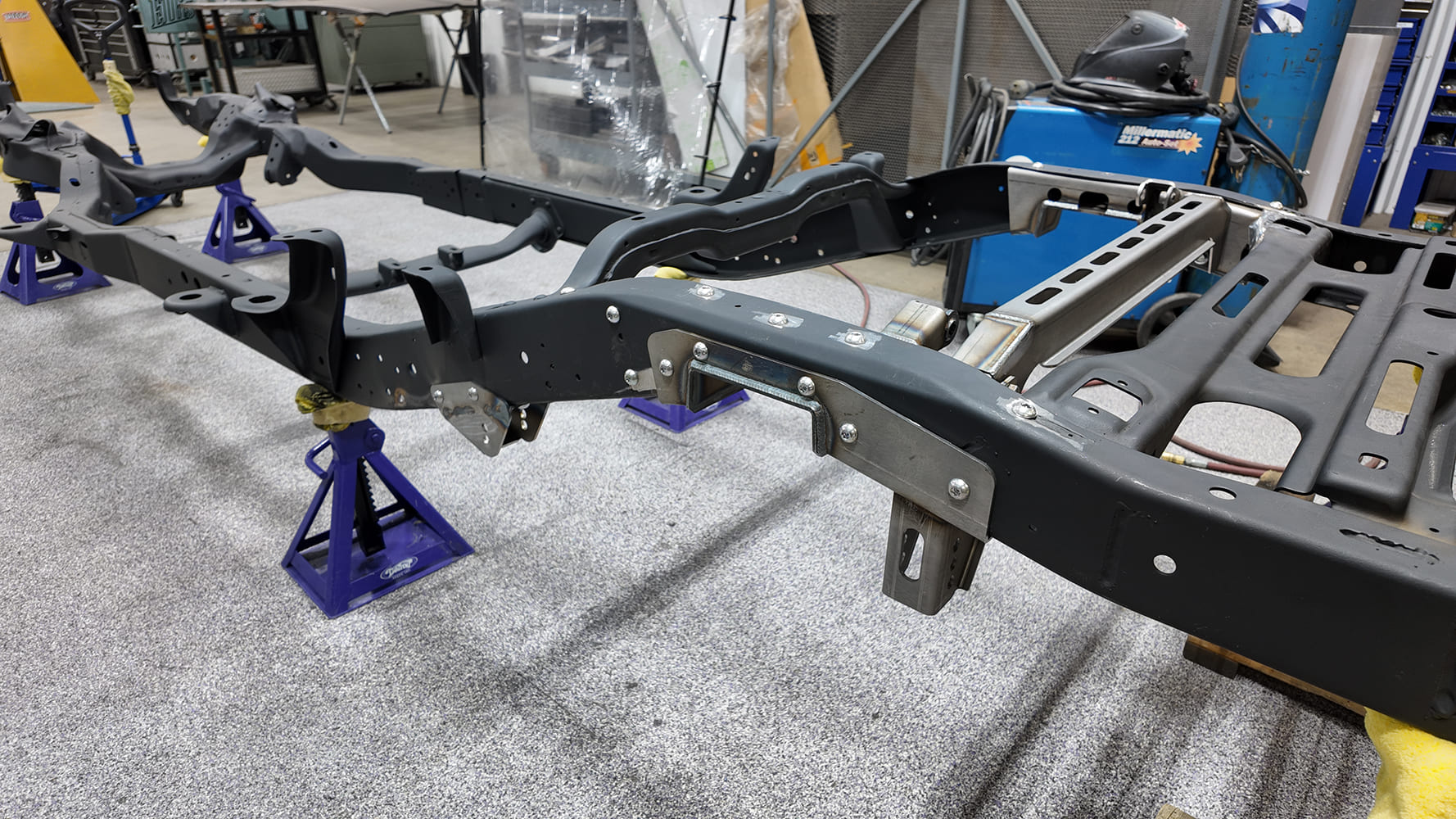 S-10 suspension chassis setup showing Detroit Speed QuadraLink crossmember, frame notch brackets, and front link mounts bolted into place.