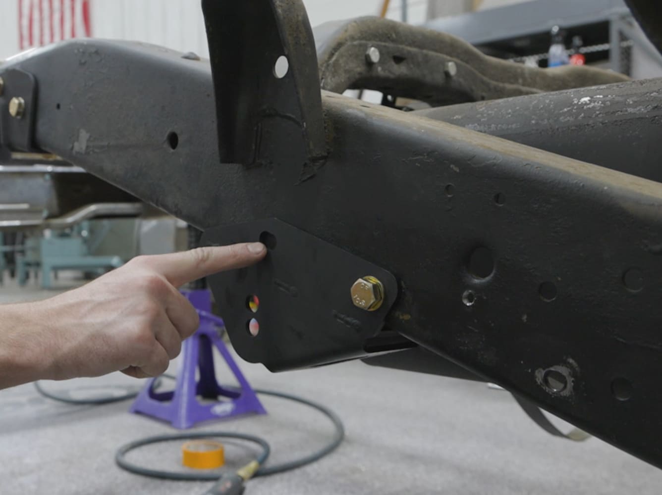 Locating and bolting the Detroit Speed QuadraLink lower link bracket onto the factory S-10 suspension frame rail.