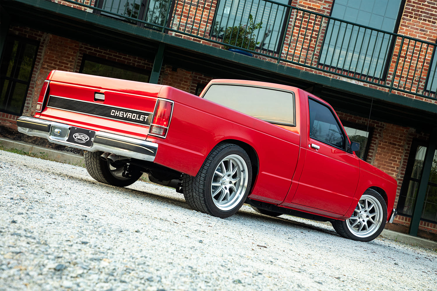 Rear three-quarter view of a lowered red Chevrolet S-10 pickup truck featuring complete Detroit Speed performance suspension.