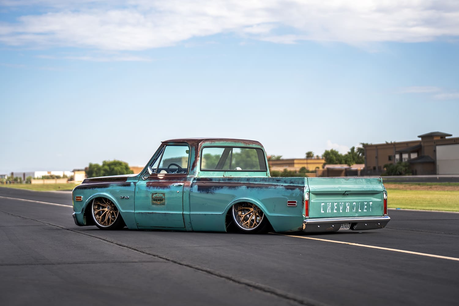 Rear three-quarter perspective of the slammed 1969 C10 showing the embossed Chevrolet tailgate and deep bronze-finished wheels tucked into the wheel wells.