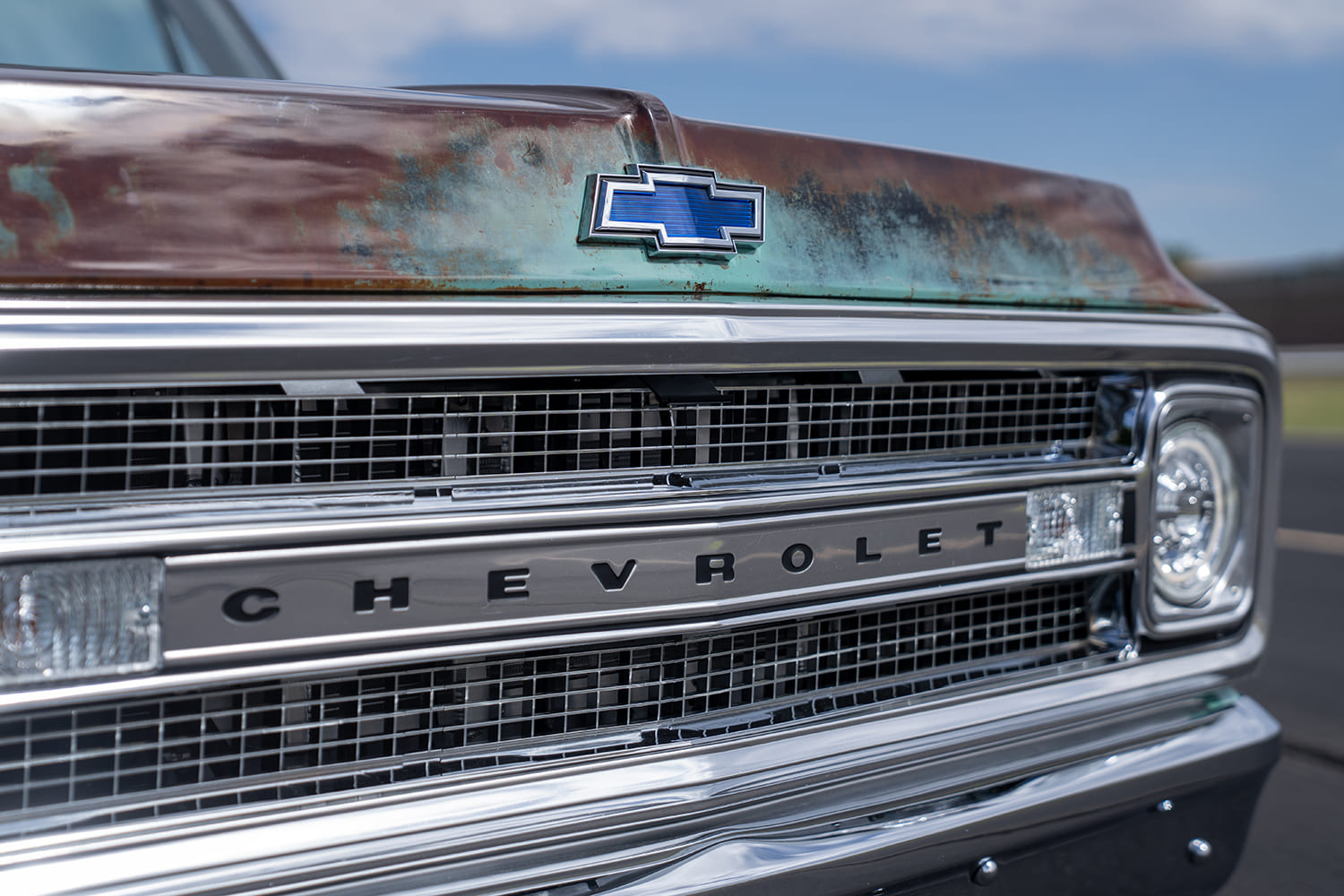 Straight-on macro shot of the bright chrome billet grille, central "Chevrolet" horizontal crossbar, modern projector headlights, and blue bowtie hood emblem.