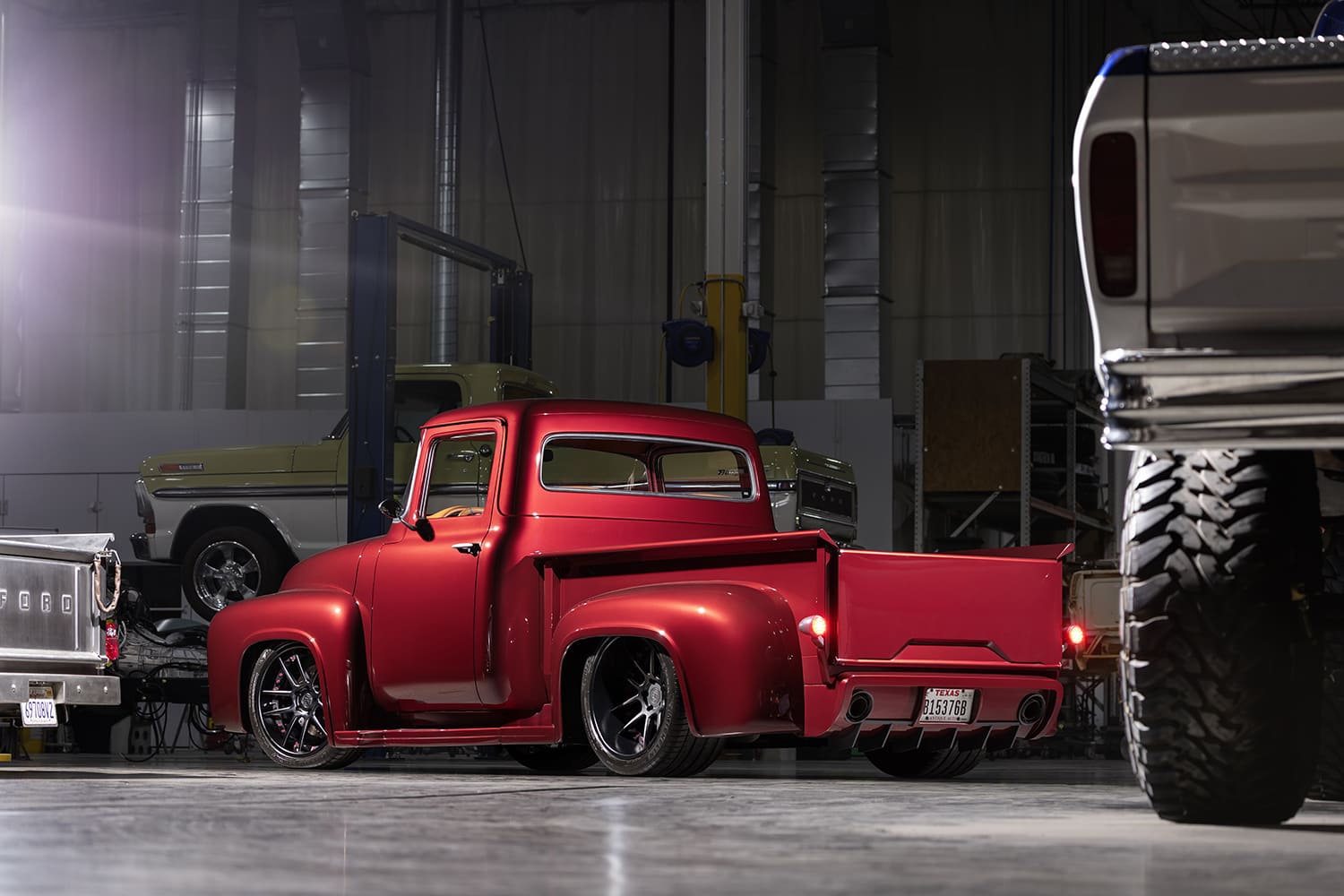 Low rear three-quarter angle highlighting the flared rear stepside fenders, massive rear tires, dual exhaust outlets, and smooth tailgate.