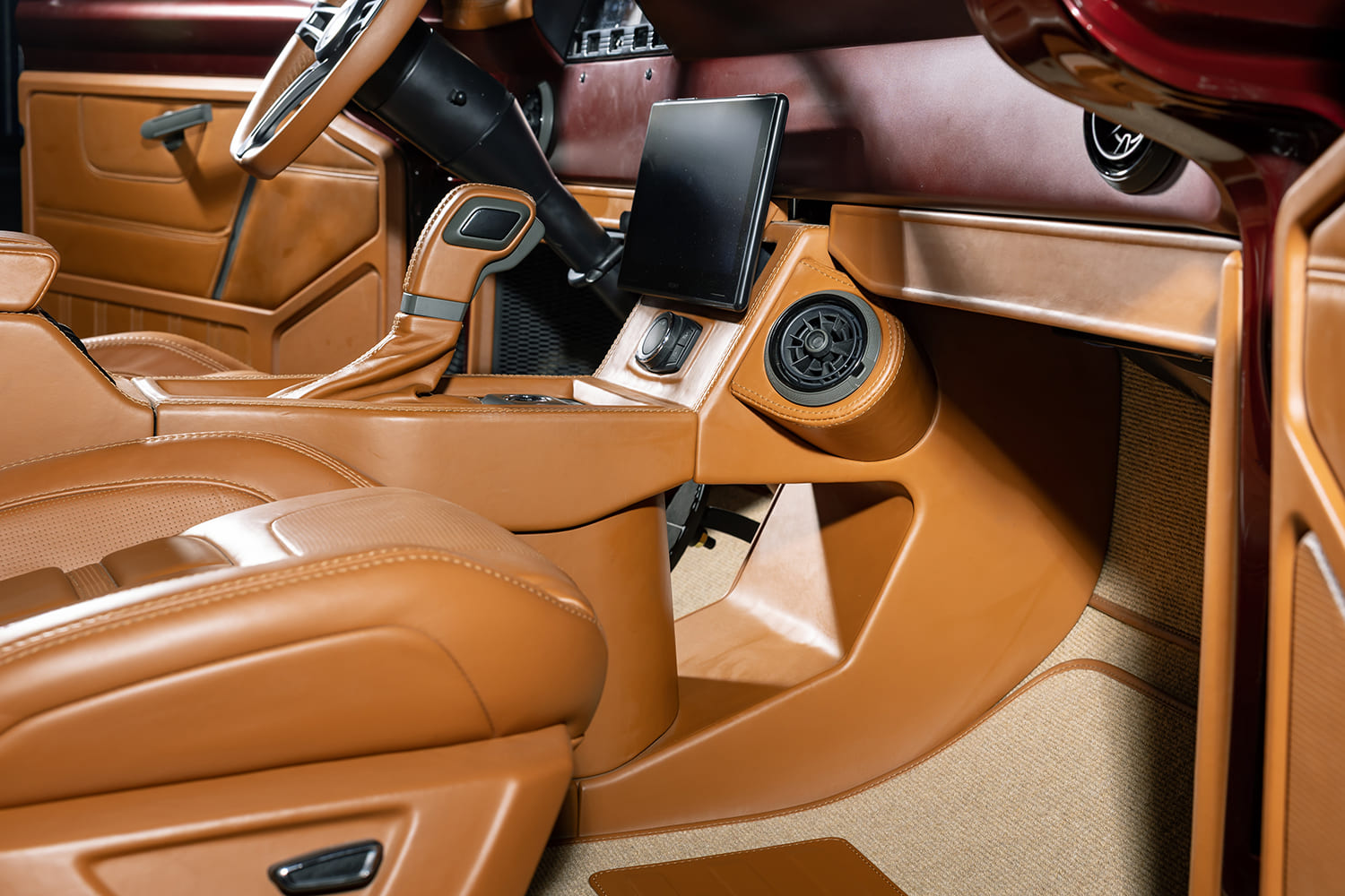 Close-up of the sculpted caramel leather center console housing an infotainment screen, A/C vent pod, and automatic shifter in the Ford cab.