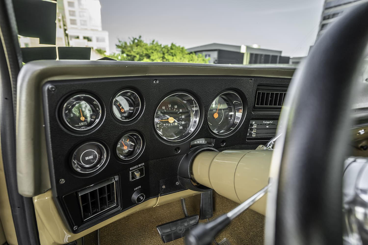 Detailed close-up of the black bezel instrument cluster featuring modern analog gauges with orange needles, speedometer, and Vintage Air climate controls.