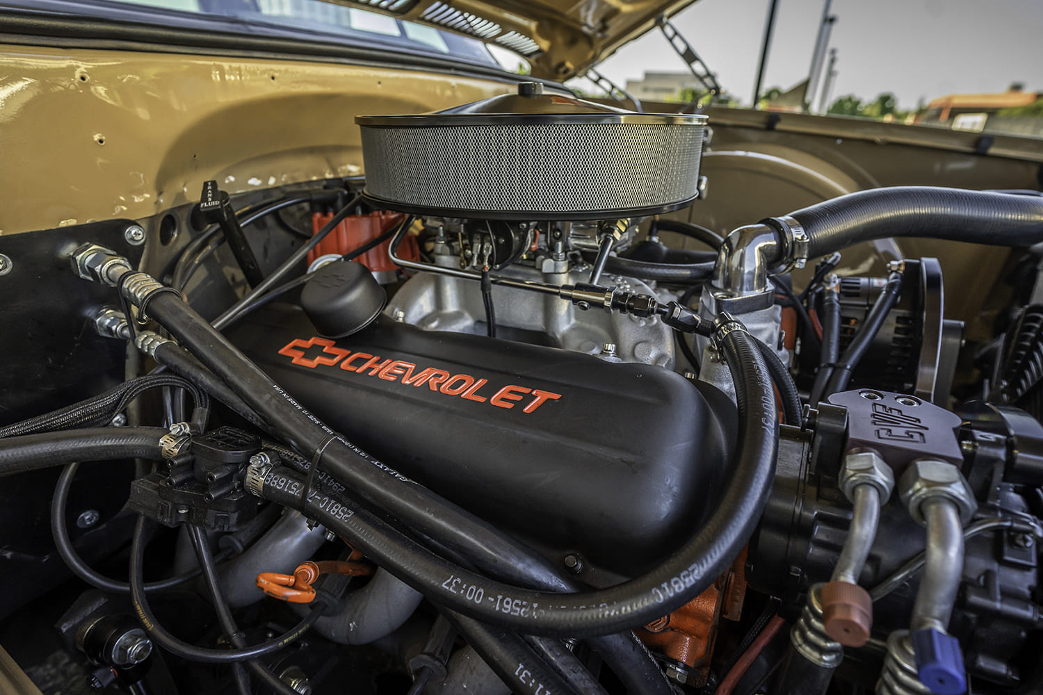 Macro view of the matte black Chevrolet-script valve cover, aluminum intake manifold, open air filter assembly, and CVF serpentine drive.
