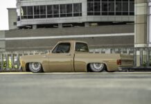 Low driver-side ground-level profile of Darren Harden’s 1973 Chevy Squarebody sitting completely flat on the asphalt with both 22-inch steelies tucked.