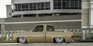 Low driver-side ground-level profile of Darren Harden’s 1973 Chevy Squarebody sitting completely flat on the asphalt with both 22-inch steelies tucked.